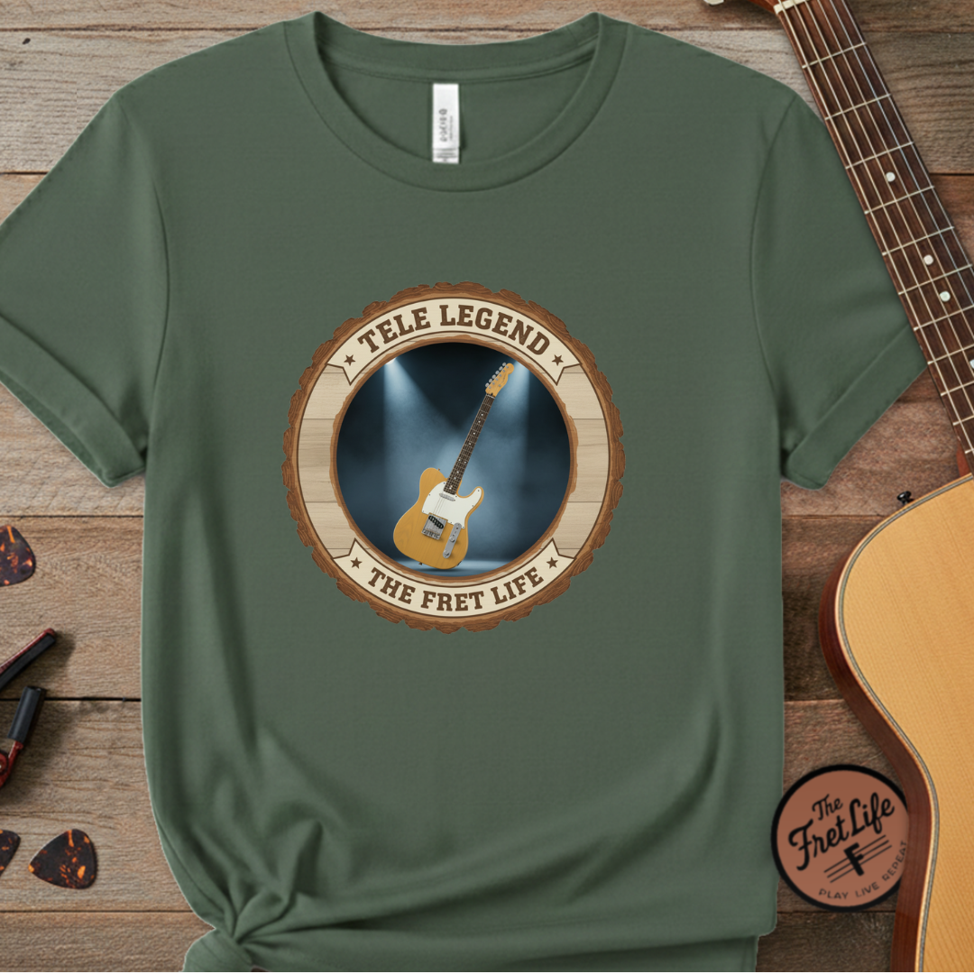 Green t-shirt with guitar graphic and text on a wooden surface with a guitar.