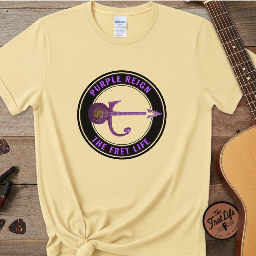 Beige t-shirt with 'Purple Reign The Fret Life' graphic on a wooden surface with a guitar.