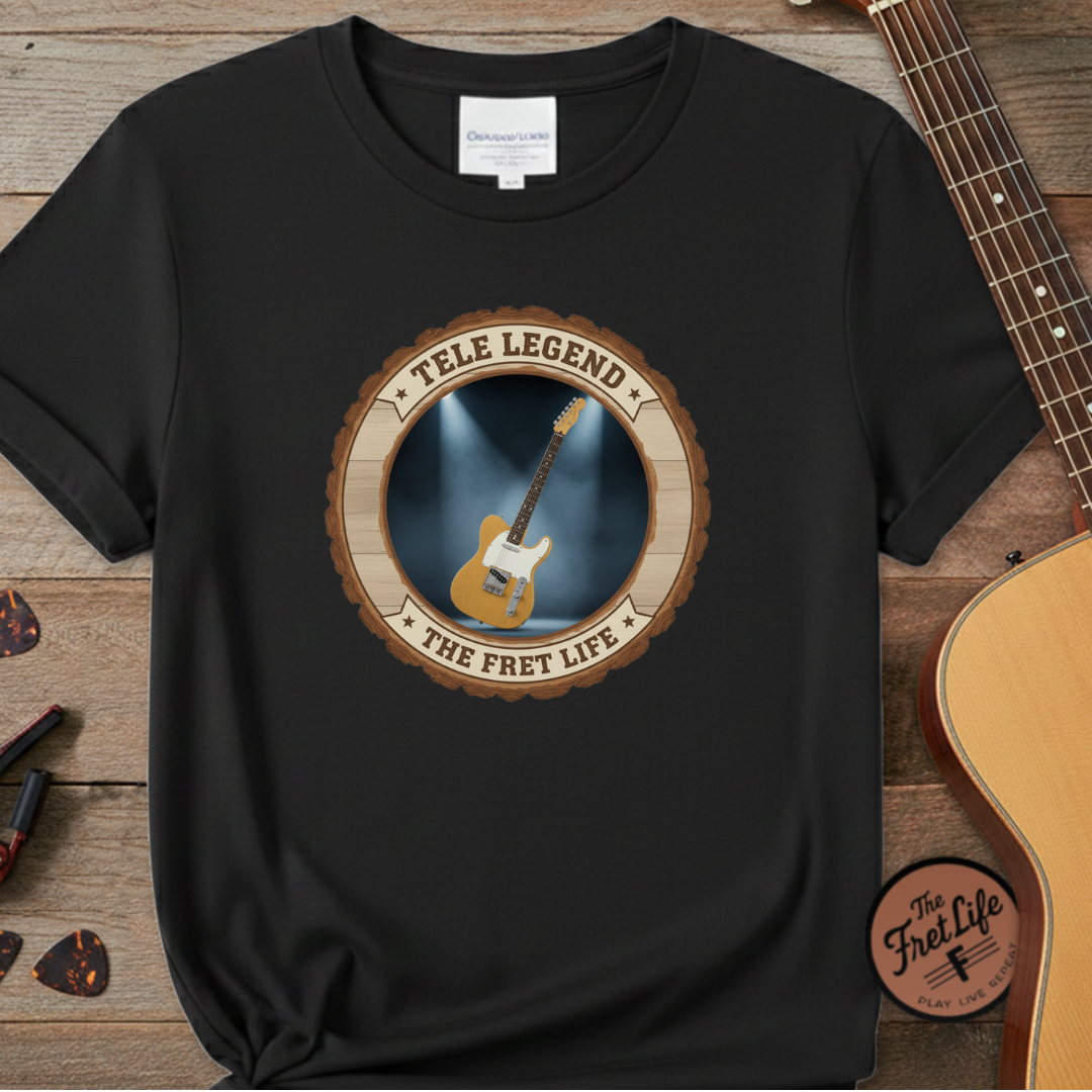 Black t-shirt with guitar graphic and text 'Tele Legend The Fret Life' on a wooden surface with a guitar.