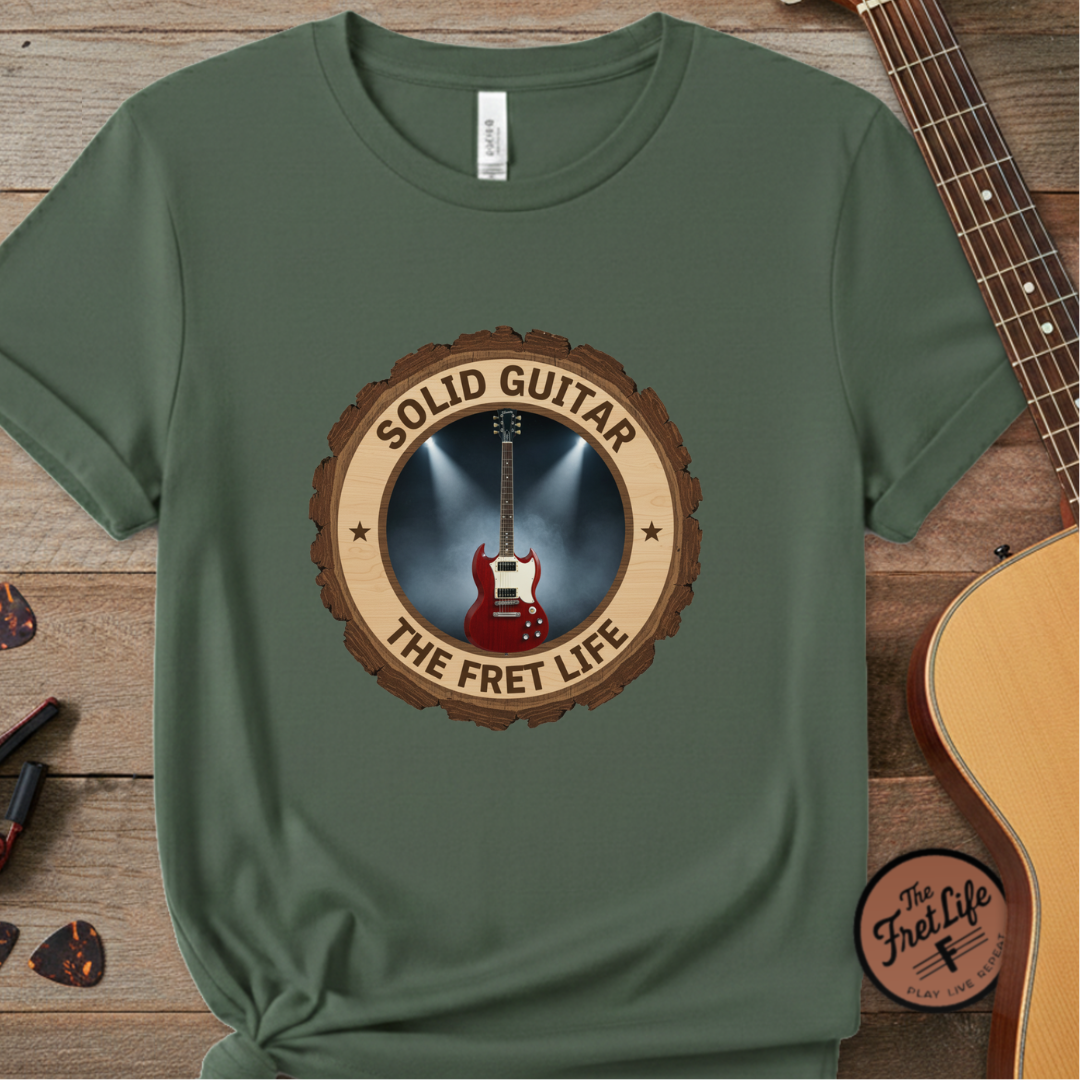 Green t-shirt with guitar graphic and 'Solid Guitar The Fret Life' text on a wooden background