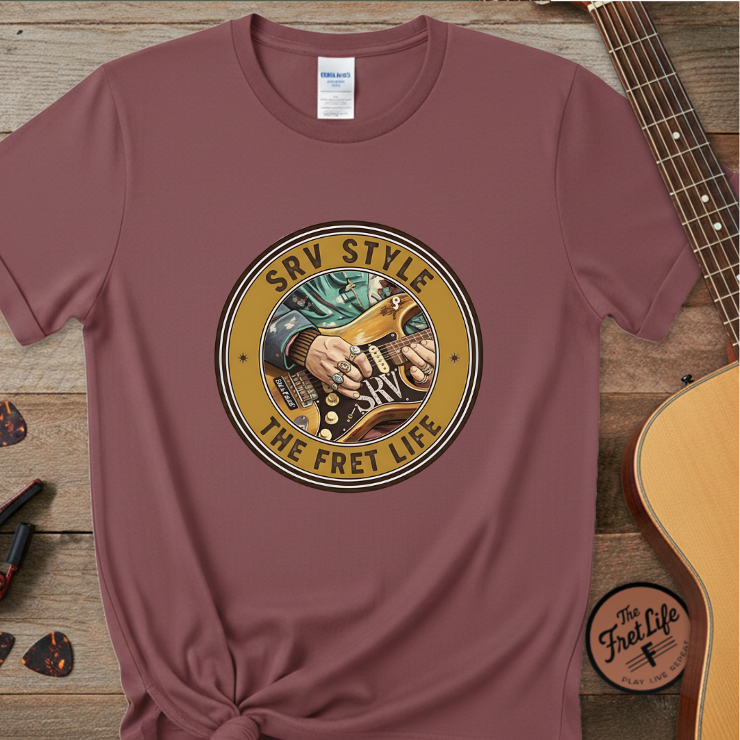 Maroon t-shirt with 'SRV Style The Fret Life' graphic on a wooden surface with a guitar.
