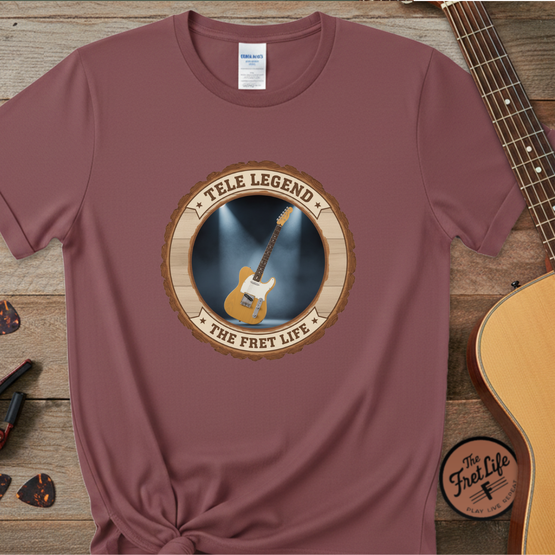 Maroon t-shirt with guitar graphic and 'The Fret Life' text on a wooden surface with a guitar.