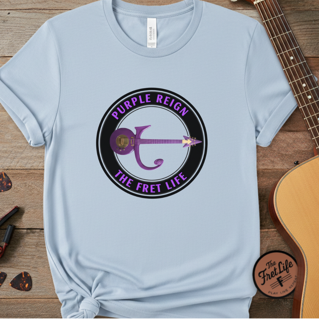 Light blue t-shirt with 'Purple Reign The Fret Life' design on a wooden surface with a guitar.