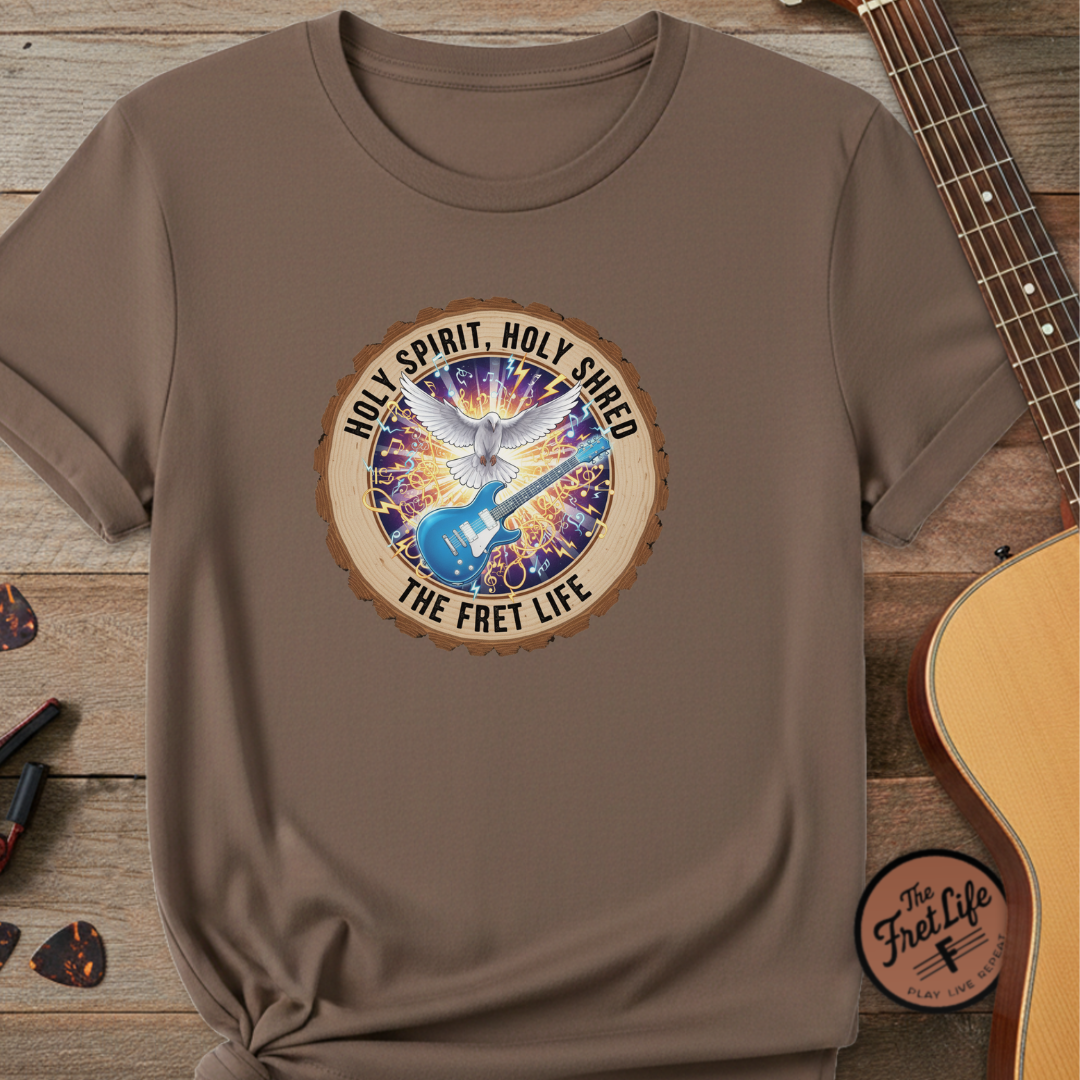 Brown t-shirt with a colorful graphic and text on a wooden surface with a guitar.