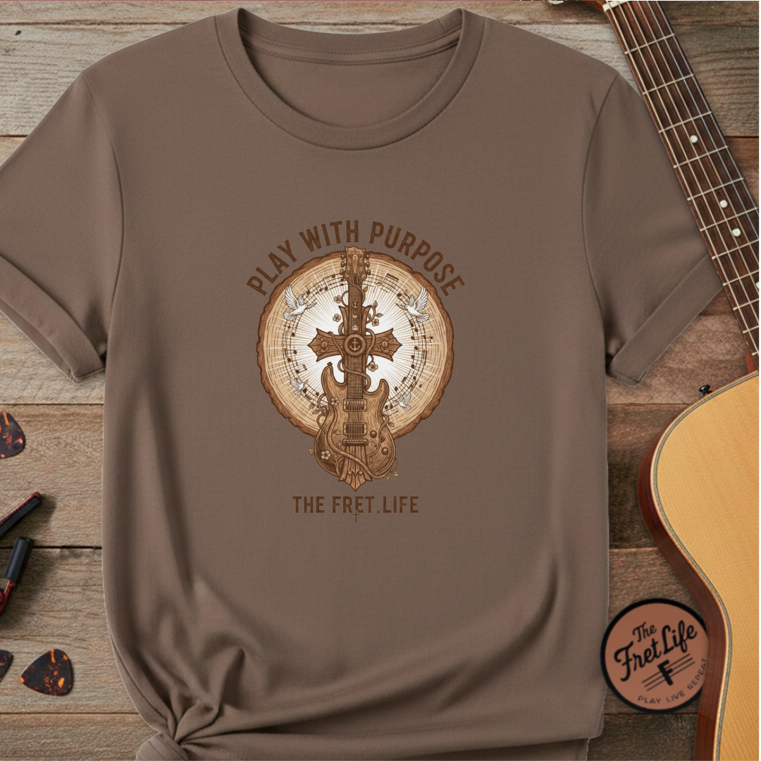 Brown t-shirt with guitar graphic and text on a wooden surface with a guitar.