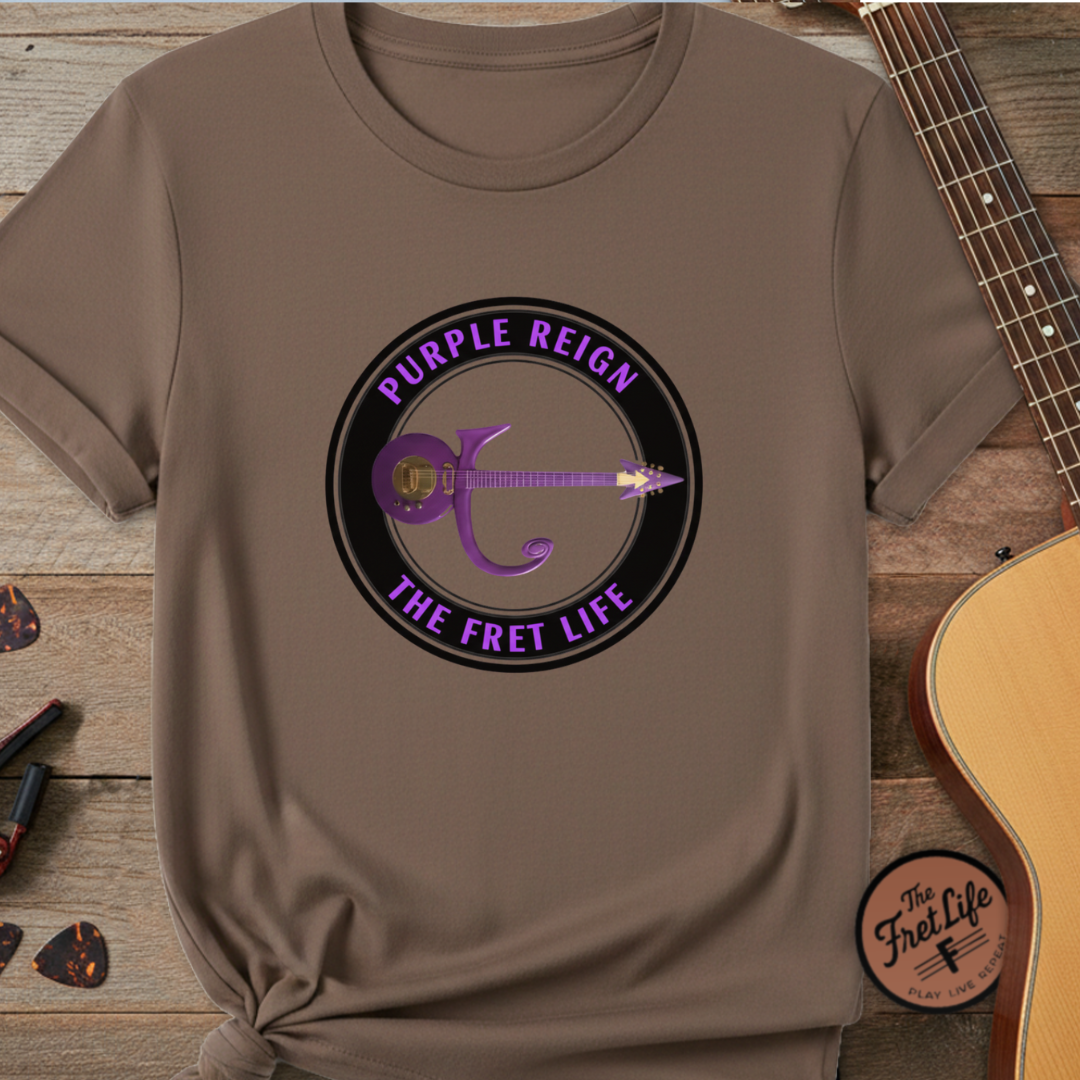 Brown t-shirt with 'Purple Reign The Fret Life' graphic on a wooden surface with a guitar.