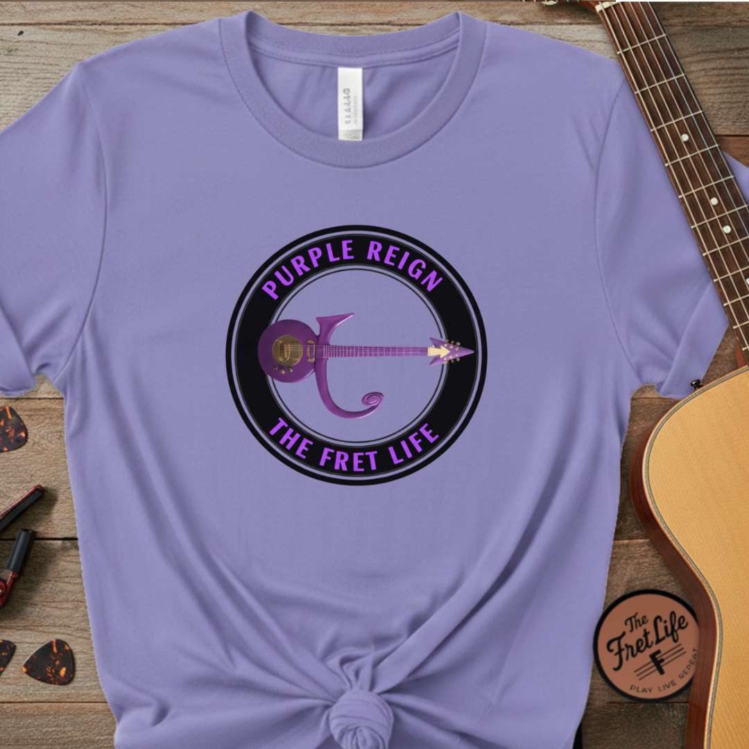 Purple t-shirt with guitar graphic and text on a wooden surface with a guitar