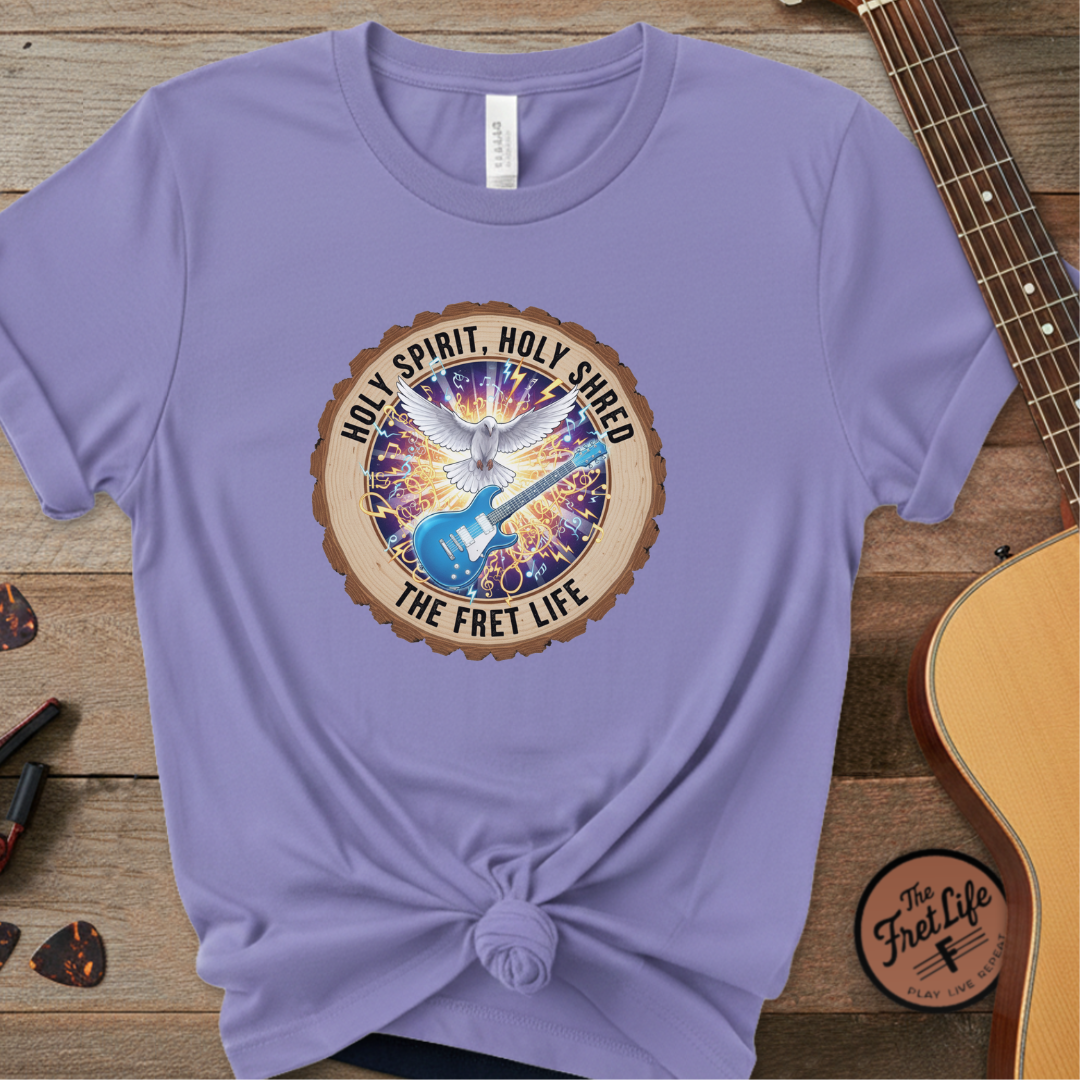 Purple t-shirt with a graphic design featuring a guitar and text on a wooden surface with a guitar.