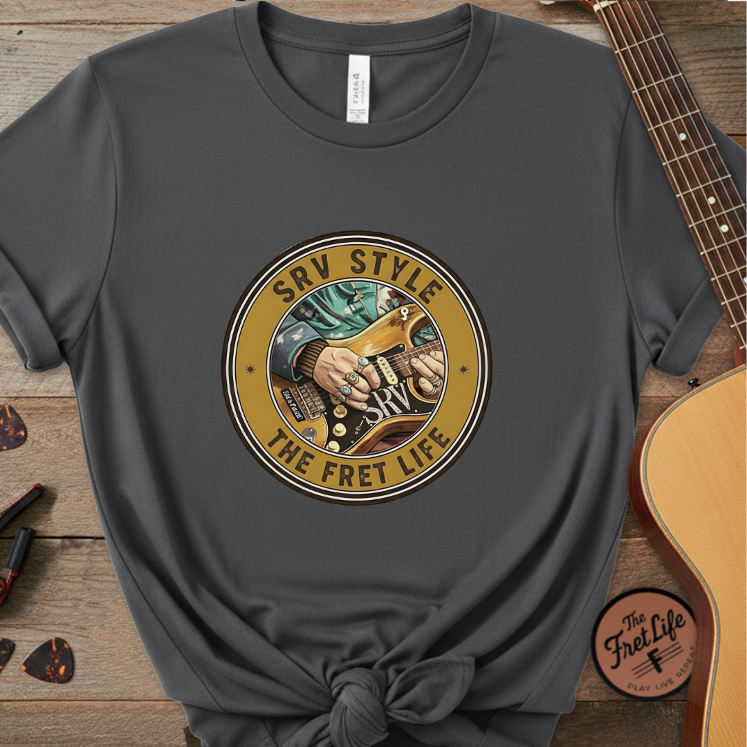 Gray t-shirt with a guitar-themed graphic and text on a wooden surface with a guitar.