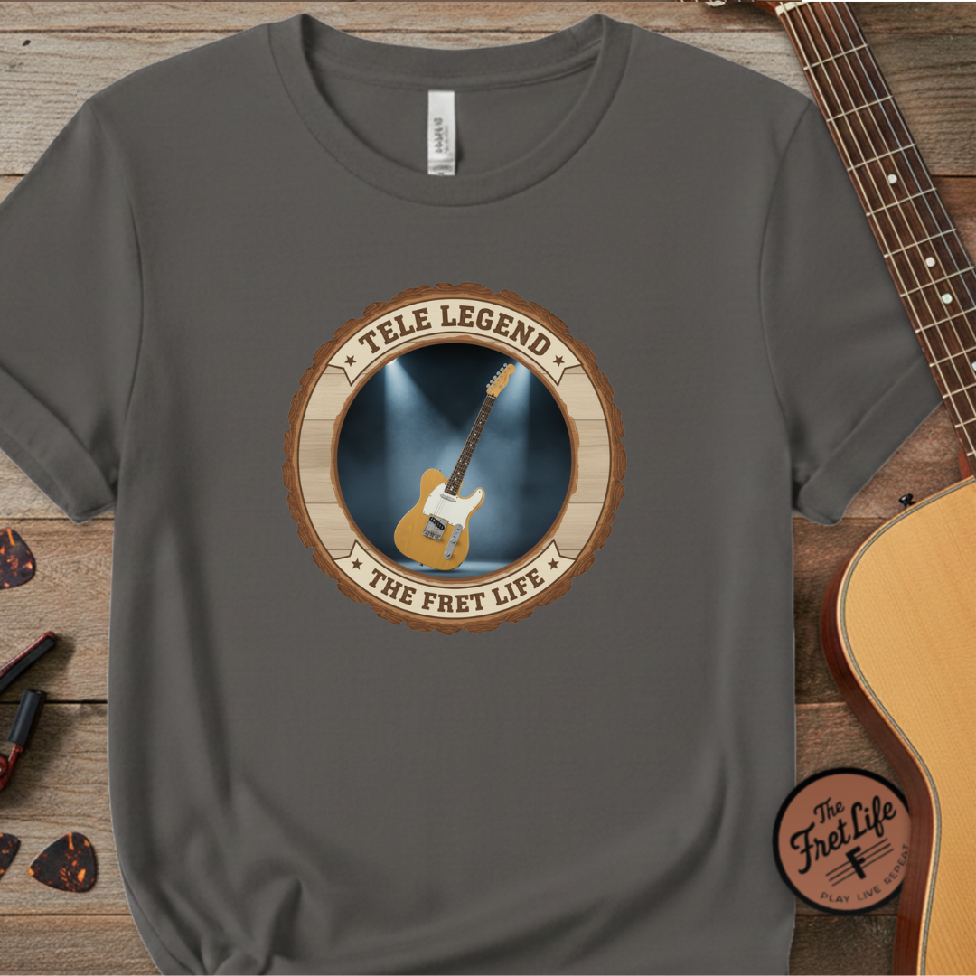 Gray t-shirt with guitar graphic and 'The Fret Life' text on a wooden surface with a guitar.