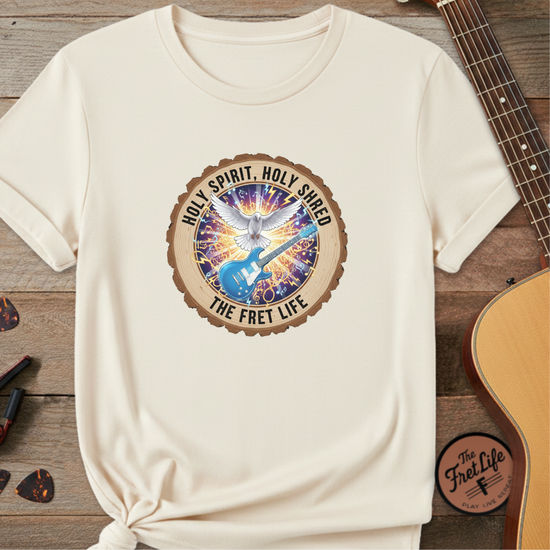 Beige t-shirt with a graphic design featuring a guitar and text on a wooden surface with a guitar.