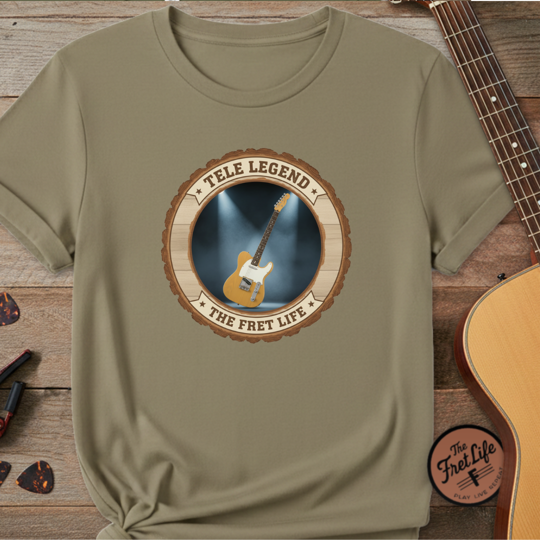 Khaki t-shirt with 'Tele Legend' graphic on a wooden surface with a guitar