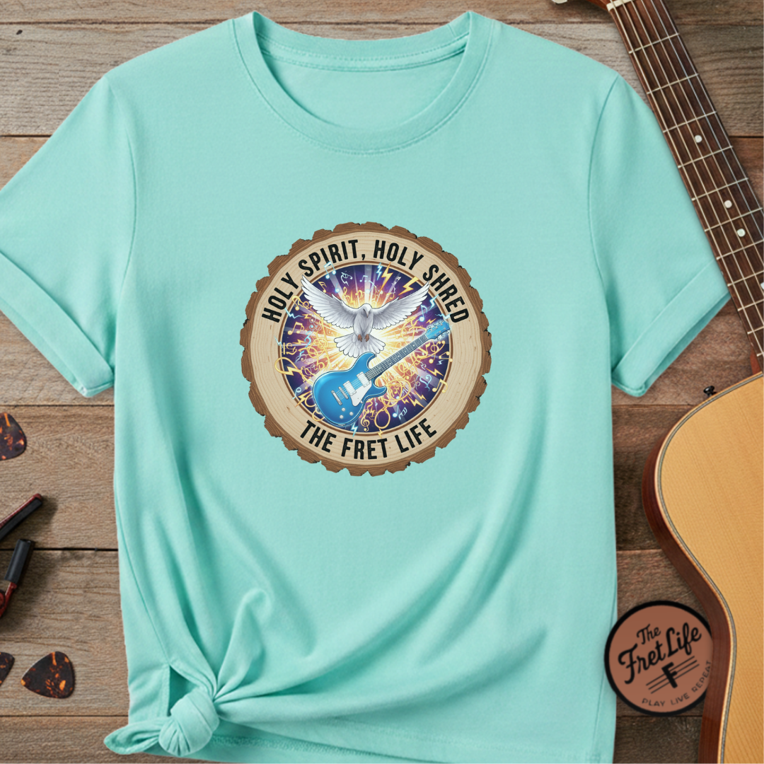 Light blue t-shirt with a graphic design featuring a dove and text on a wooden surface with a guitar.