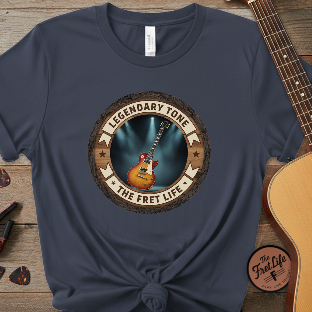 Navy blue t-shirt with 'Legendary Tone' graphic on a wooden surface with a guitar.