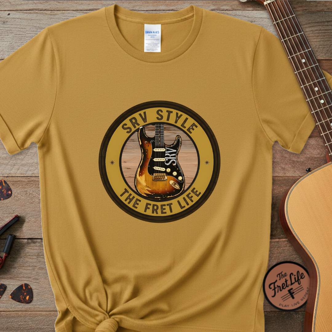 Yellow t-shirt with guitar graphic and text on a wooden surface with a guitar.