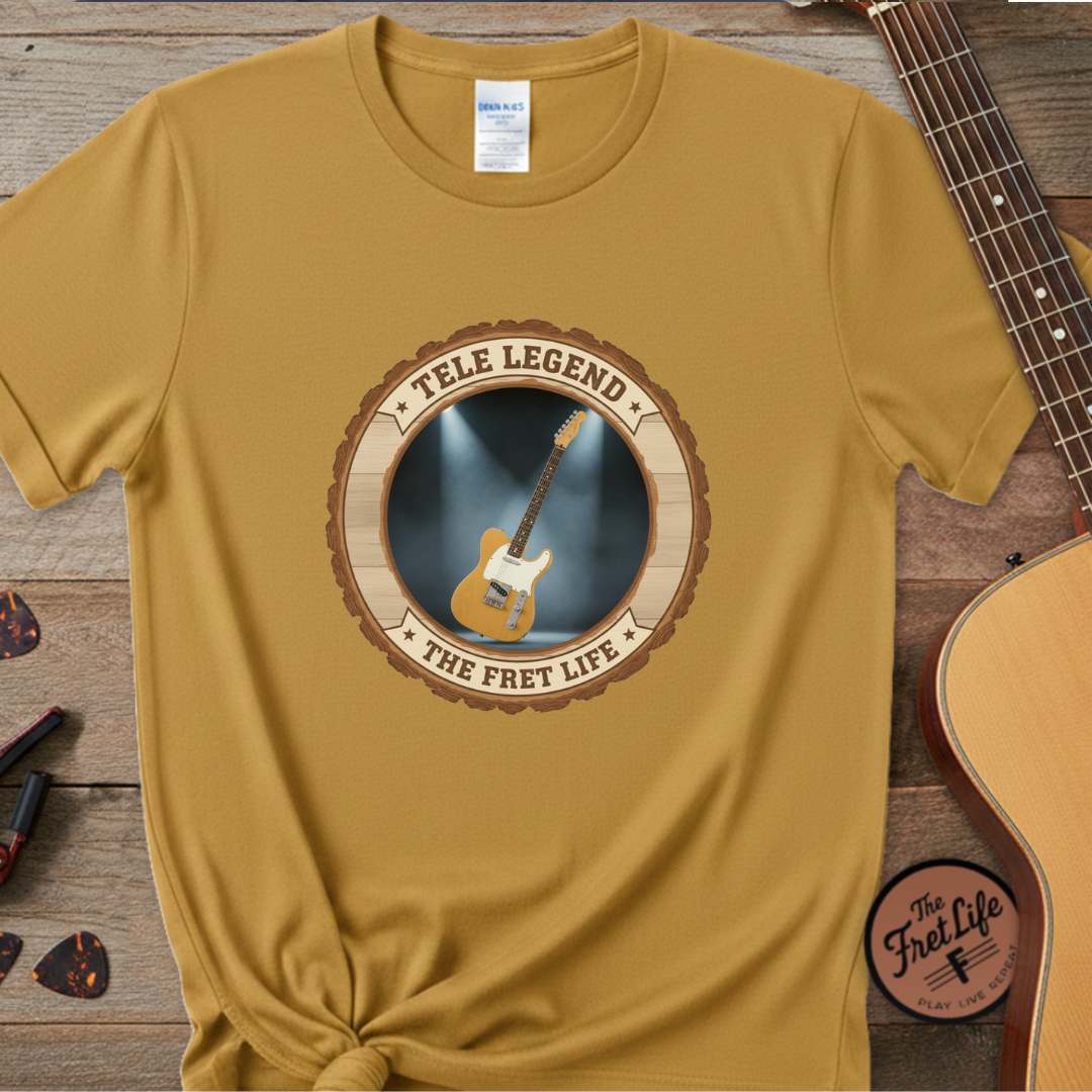 Yellow t-shirt with guitar graphic and text on a wooden surface with a guitar.