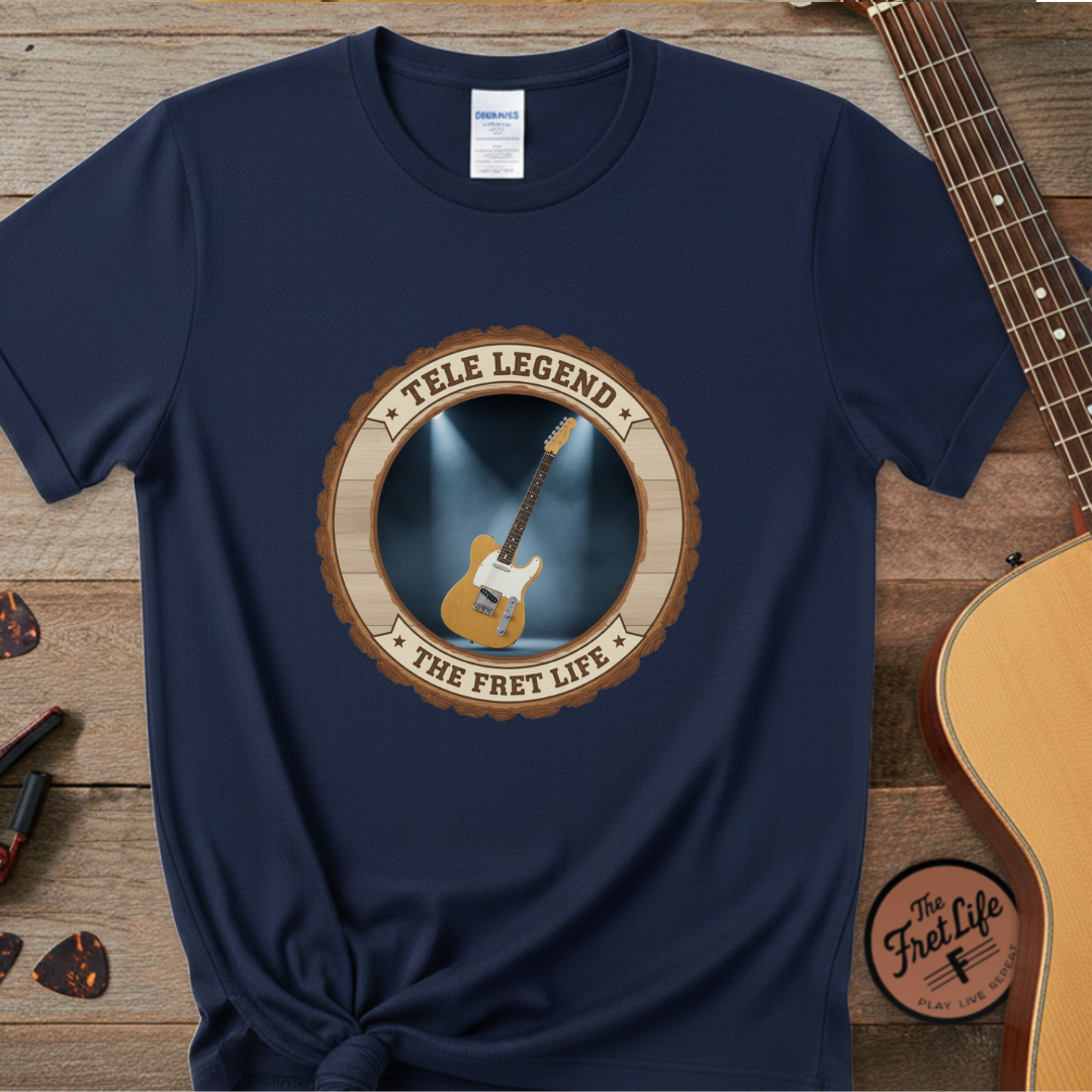Navy blue t-shirt with 'Tele Legend' graphic on a wooden surface with guitars.