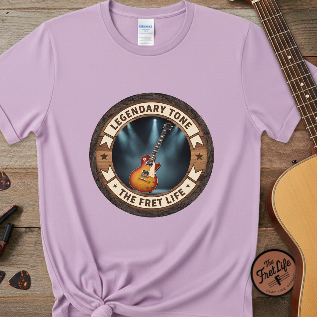 Purple t-shirt with 'Legendary Tone The Fret Life' graphic on a wooden surface with a guitar.