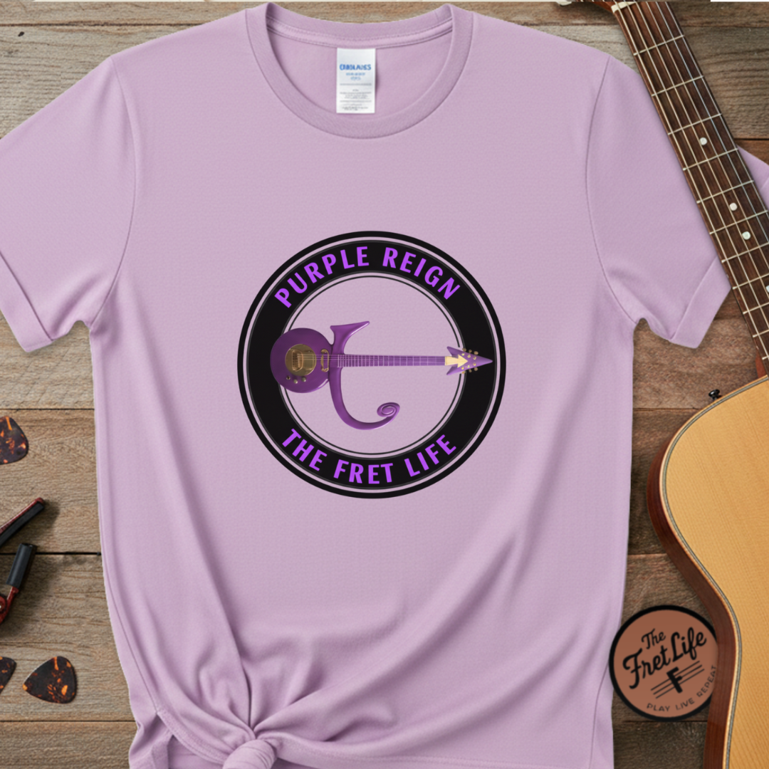 Purple t-shirt with 'Purple Reign The Fret Life' design on a wooden surface with a guitar.