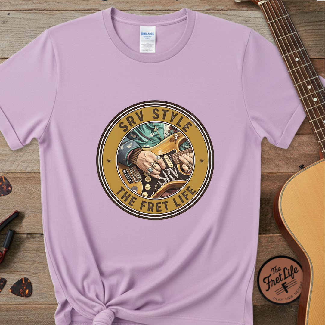 Purple t-shirt with 'SRV Style The Fret Life' graphic on a wooden surface with a guitar.
