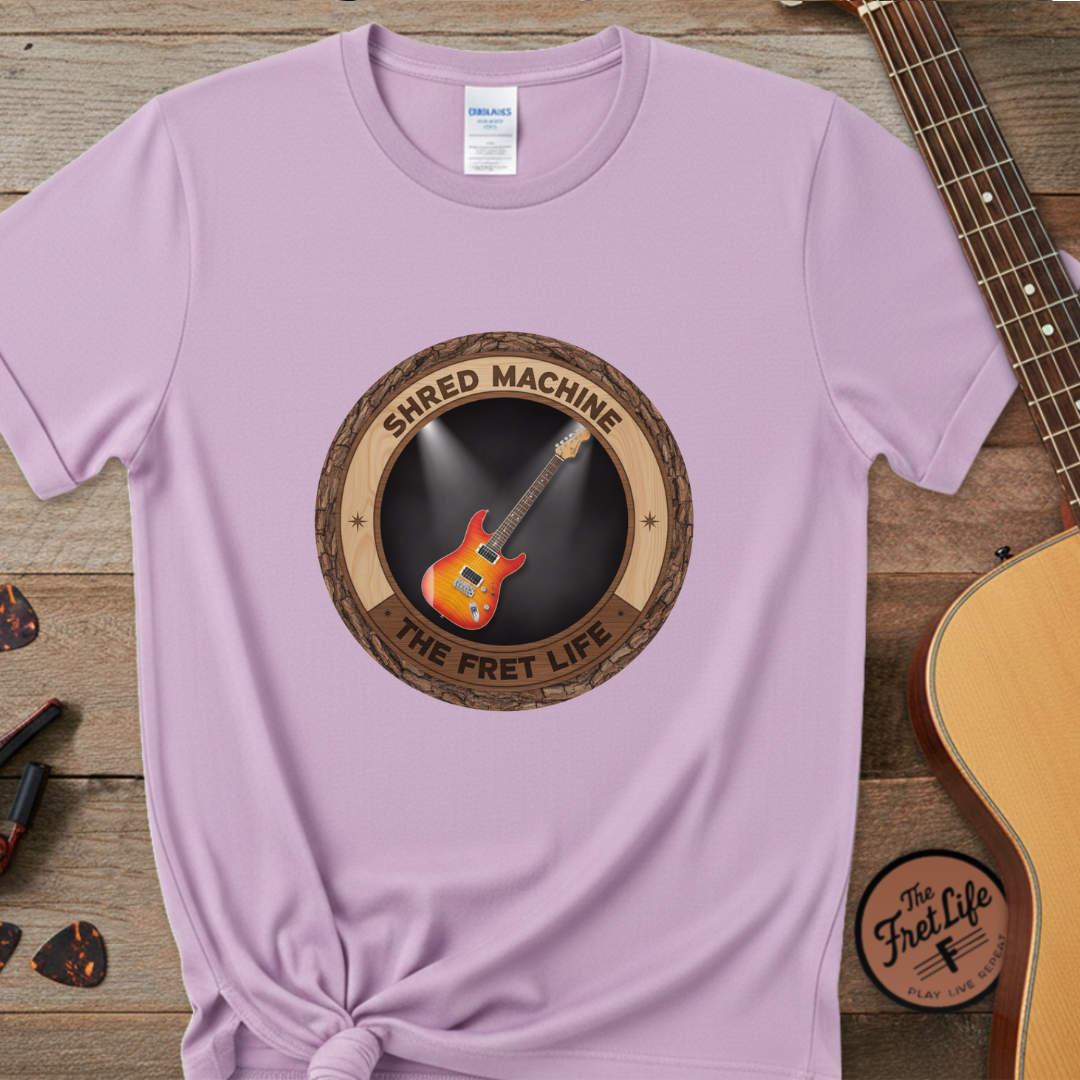 Purple t-shirt with guitar graphic and 'Shred Machine' text on a wooden surface with a guitar.
