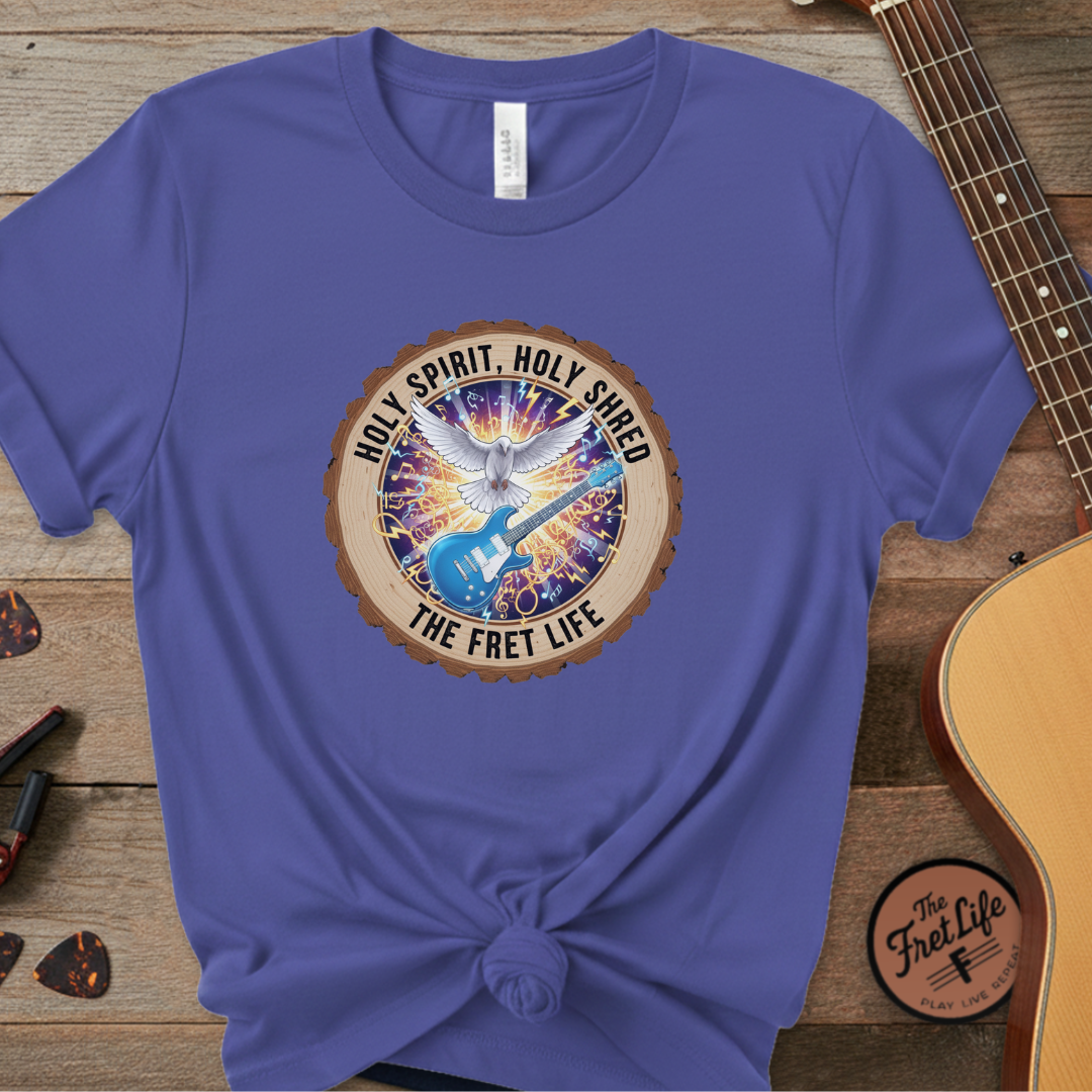 Blue t-shirt with a graphic design on a wooden surface with a guitar