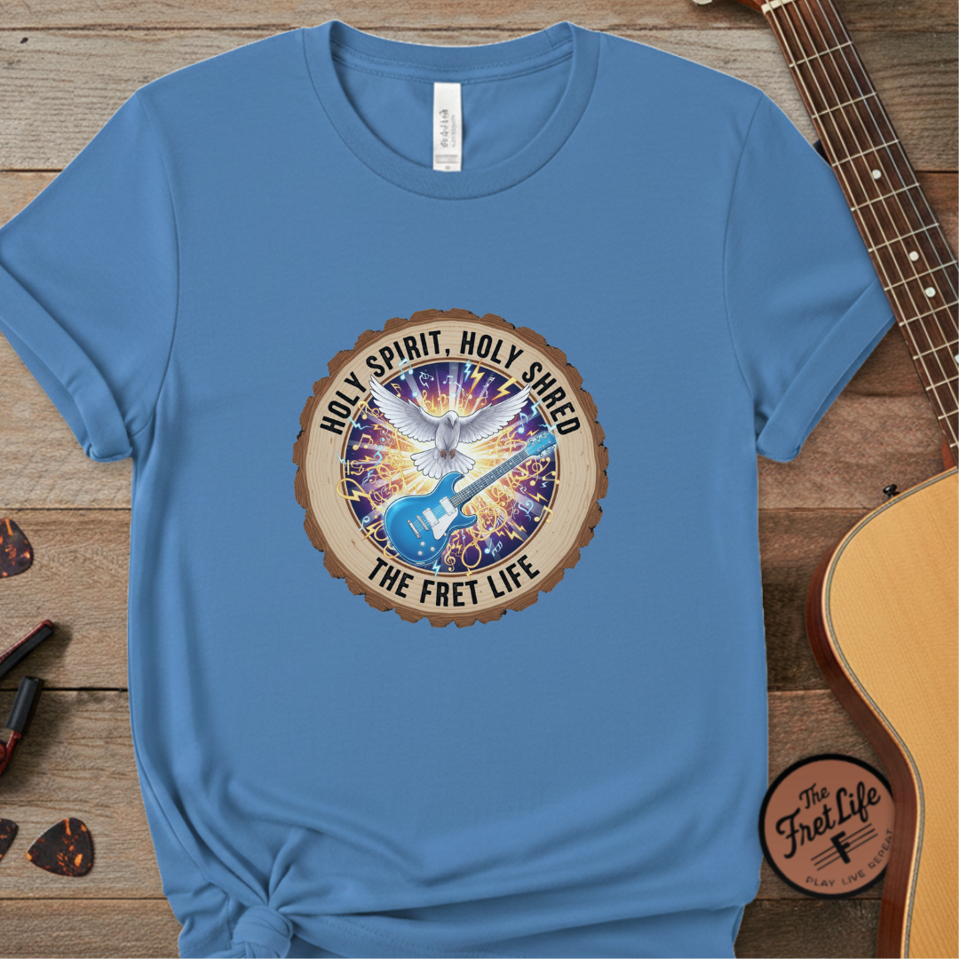 Blue t-shirt with a colorful graphic design on a wooden surface with a guitar.