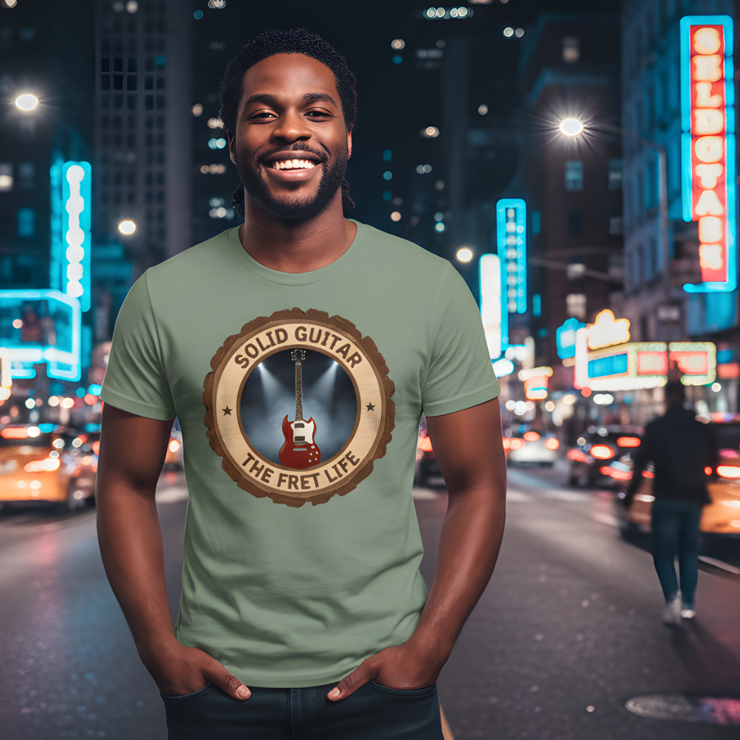 Man wearing a green t-shirt with a guitar graphic and text on a city street at night.