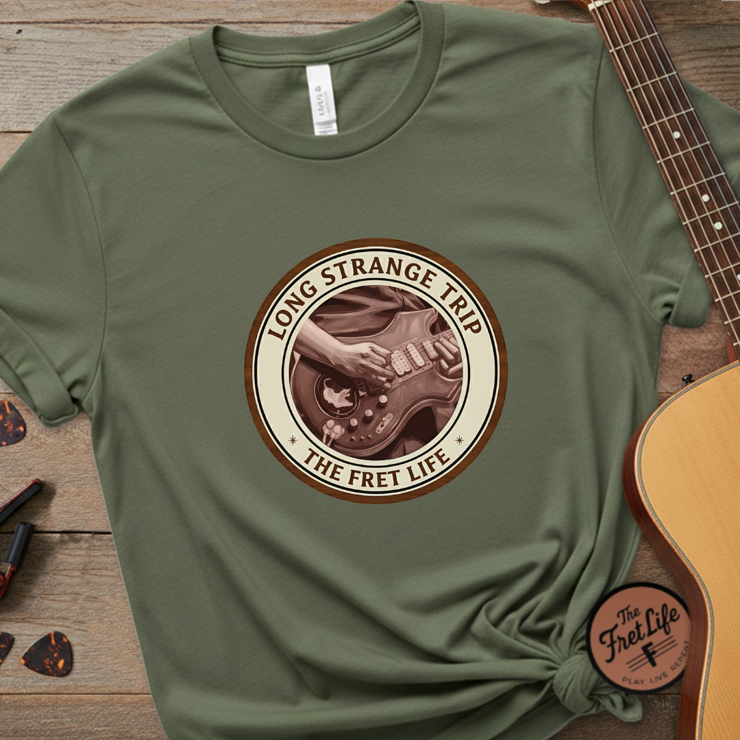 Green t-shirt with 'Long Strange Trip' graphic on a wooden surface with a guitar