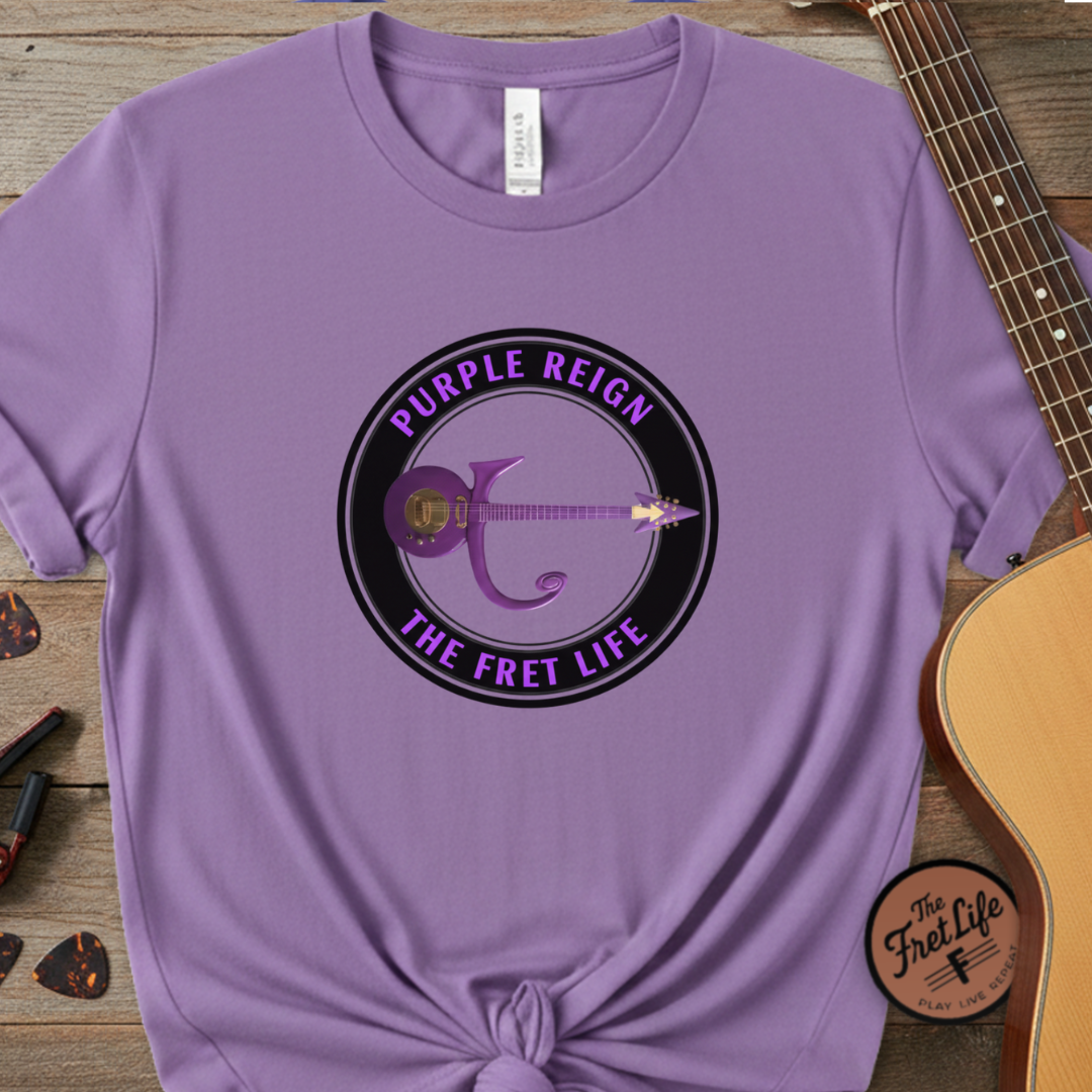 Purple t-shirt with 'Purple Reign The Fret Life' design on a wooden surface with a guitar.