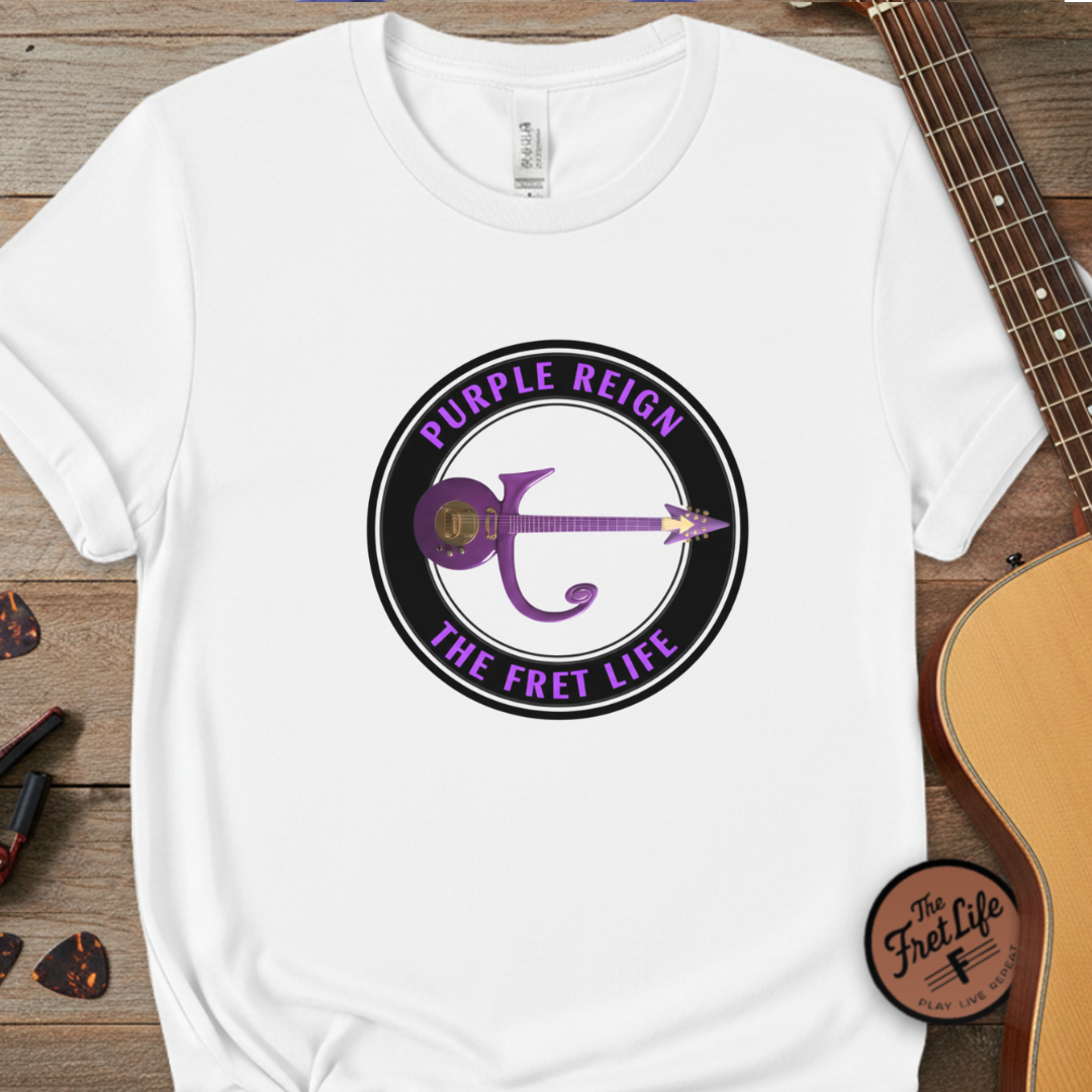 White t-shirt with 'Purple Reign The Fret Life' design on a wooden surface with a guitar.